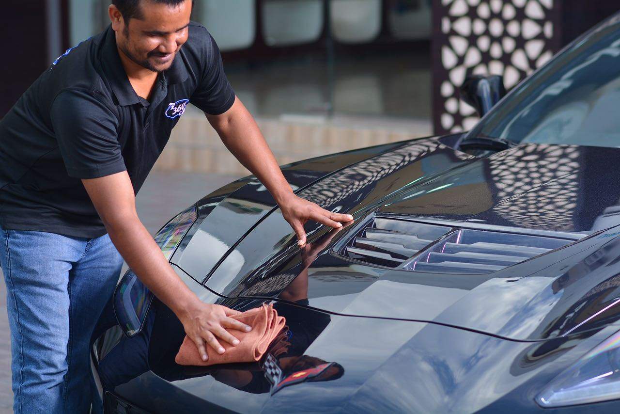 A 360 Care technician hand-finishing a black sports car