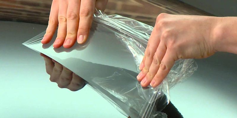 Clear urethane paint protection film being applied to a car bonnet
